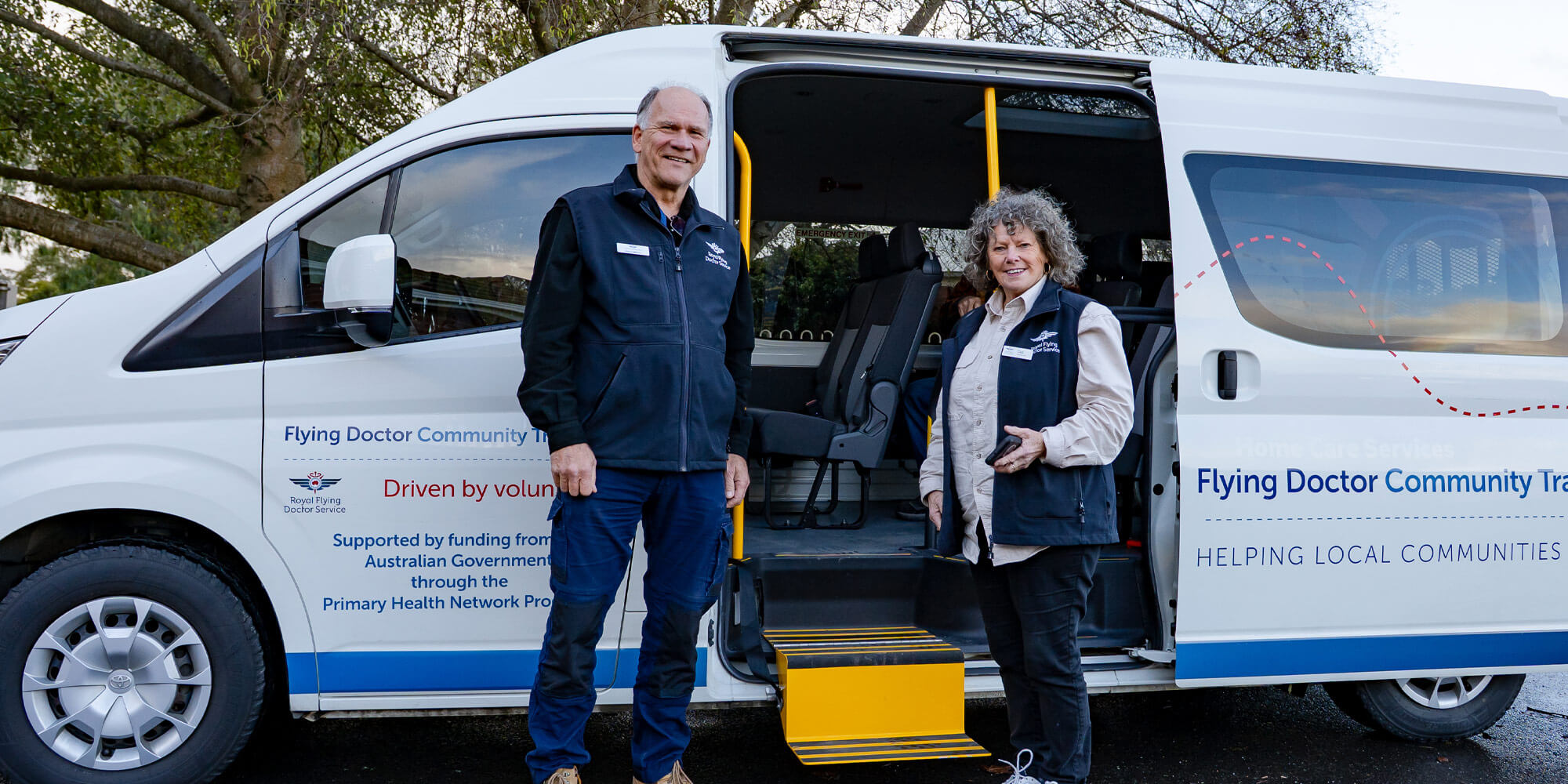 Two volunteers with the patient transport bus they operate