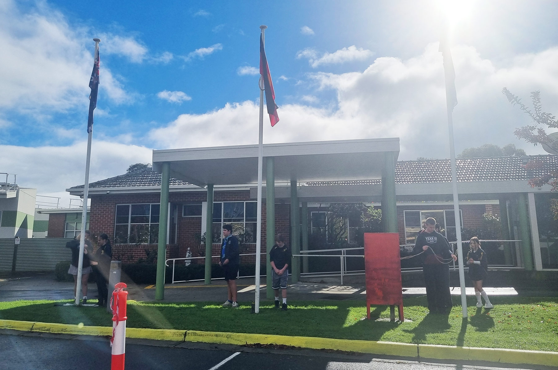 Secondary students taking part on a flag-raising ceremony in front of the hospital entrance.